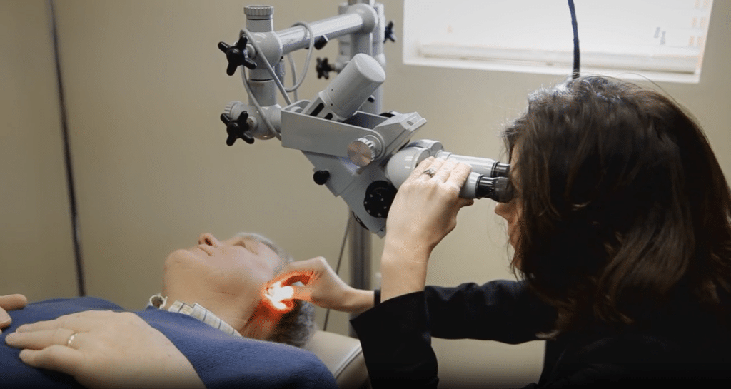 Dr. Kim Keesen examining the ear canal using a clinical microscope.
