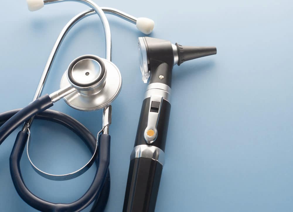 Otoscope with stethoscope on blue background.