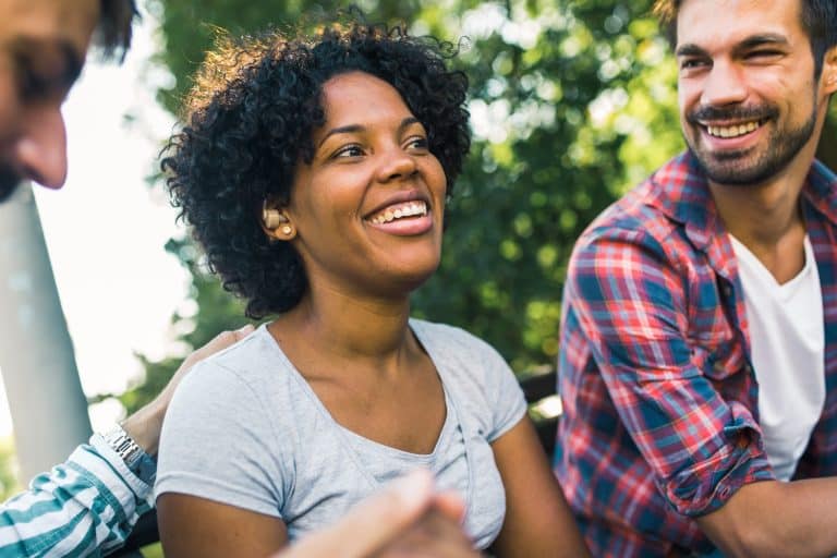 Woman with ear hearing aid having fun with her friends in the park