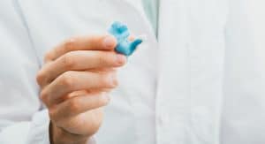 Doctor holding in his hands molded individual hearing aid earmolds for his patient, close-up.